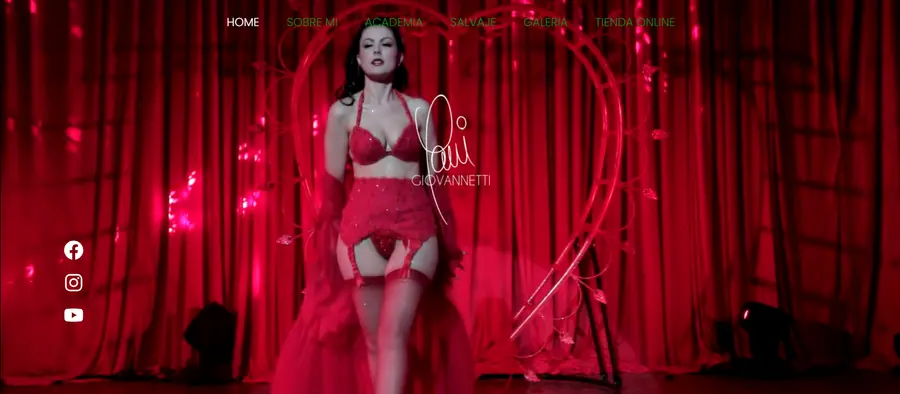 Mujer en lencería roja posando frente a un arco en forma de corazón y cortinas rojas en una página web.